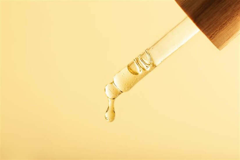 closeup photography pipette with dripping oilzeron waste wooden cover